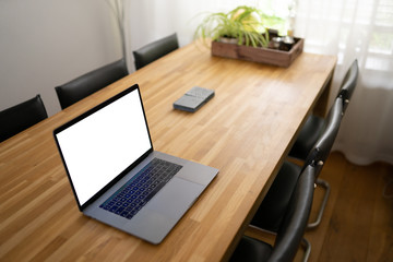 Naklejka premium A high-end modern laptop on a wooden table in the living room at home. Notebook for working at home.