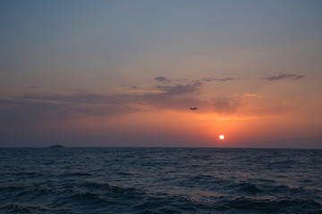 evening sunset over the sea with ship and plane