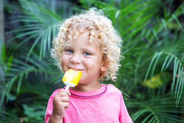  little boy with blonde curly hair is eating ice cream