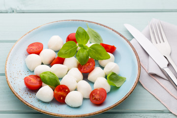 Delicious caprese salad with ripe cherry tomatoes and mini mozzarella cheese balls with fresh basil leaves.