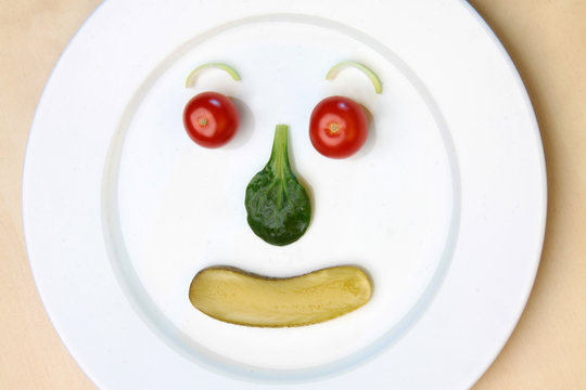 Gemüse zu einem Gesicht auf einem runden Teller dekoriert