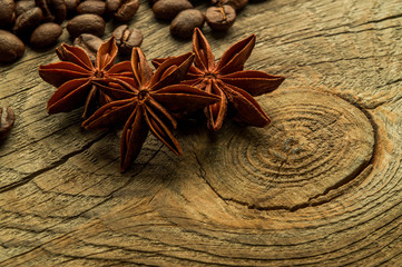 Coffee beans and three star aniseas closeup on a wooden board, with blurred depth of field. The concept of taste of coffee.