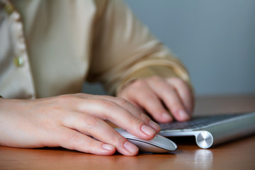 Image of female hands pushing keys of a computer mouse and keyboard