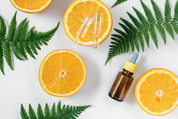Citrus essential oil, vitamin c serum with fresh juicy orange fruit and leaf fern on white background. Organic Spa Cosmetic With Herbal Ingredients Toning. High dose vitamin c synthetic for skin - obrazy, fototapety, plakaty
