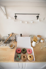 Obraz na płótnie Canvas From above shot of open box with delicious fresh donuts lying on wooden tabletop in kitchen