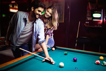 Fototapeta premium Happy young man playing snooker with his girlfriend. Happy loving couple.