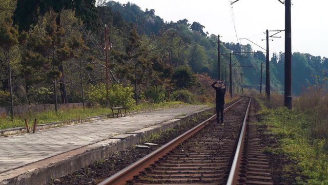 Man walks along railroad tracks and take a photo