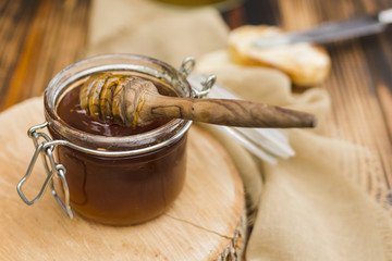 Glass jar full of honey with honey spoon