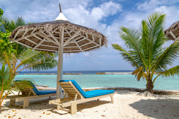 ein schöner Strand mit Sonnenschirm, Palmen und Liegen