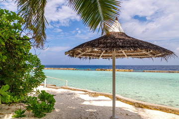 ein schöner Strand mit Sonnenschirm und  Palmen