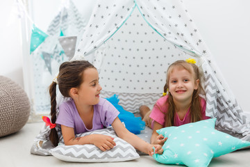 Two cute happy girls play at home. Funny lovely sisters are having fun in children room. Girls play