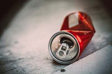 crumpled red can of drink lies on a white surface