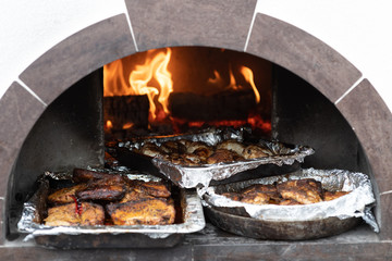 trays of cooked meat in the oven on the coals.