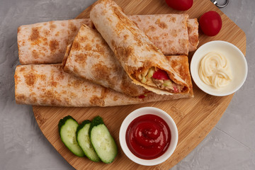 Shawarma, fresh roll of pita, chicken, vegetables. Traditional Middle Eastern snack on a wooden board