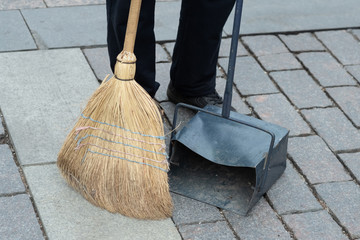 municipal worker sweep the road with broomstick and collects garbage in scoop. sanitation worker...