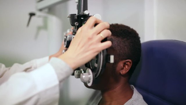 front view of an afro woman in an optometry cabinet correcting her eyesight