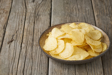 crisp in bowl, wooden background, closeup, copy space
