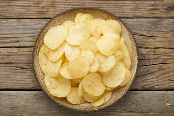 crisp in bowl, wooden background, top view
