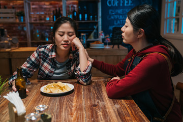 Young woman staff working in night beer bar helping her drunk friend at table counter. sad lady sister heart broken break up with boyfriend lover end relationship waitress comforting consoling in pub