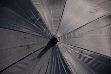 Raindrops falling on black umbrella outdoors.