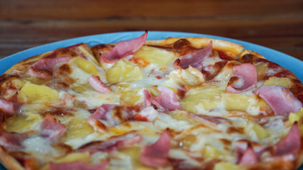 Homemade hawaiian Pizza, pineapple, ham and cheese on wooden table.