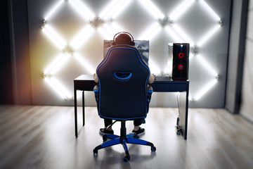 Professional gamer in his expensive studio young man having live stream playing online video game. Cyber sportsman is streaming popular pc computer game for his followers     © D'Action Images