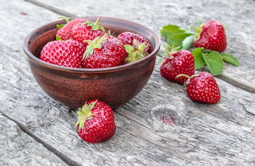 Fresh strawberries in a bowl on a wooden table.