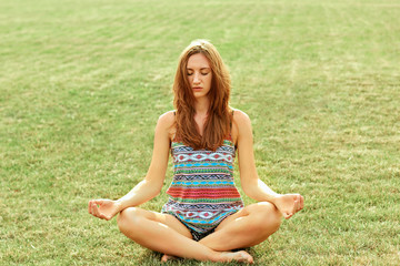 Beauty woman practices yoga and meditates in the lotus position in the park. Meditation.  Active Lifestyle. Healthy and yoga concept. Fitness and sports