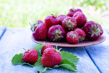 a bowl full of fresh red strawberries on blue old boards.