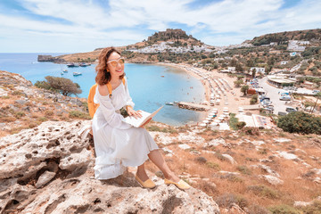 Young girl freelancer or student working with laptop computer outdoors overlooking the sea Bay and...