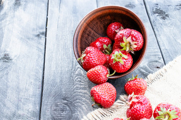 ripe red strawberries scattered on a table on burlap.
