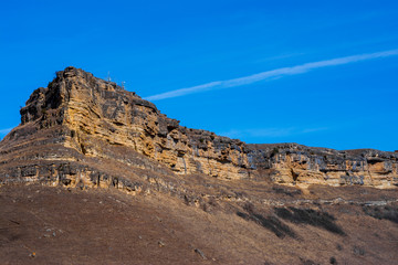 Fototapeta premium Sandy mountain with a sharp cliff and a small amount of vegetation against the blue sky