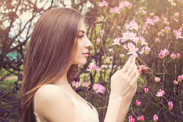 Beautiful woman face with clear skin, profile. Healthy girl sniffing flowers