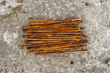 Rusty nails are stacked on a stone surface 