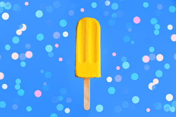 Bright yellow mango ice cream on colored confetti background.