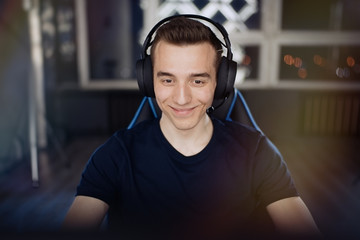 Portrait of ecstatic and smilling gamer guy in headphones while playing online video games on computer                                © D'Action Images
