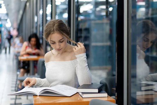 a girl in a bookstore is reading a book, preparing for a new school year. Theme education, personal development. Copy space