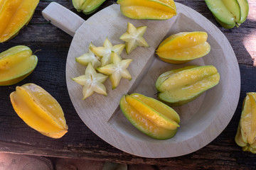 Fresh organic cut star fruit on wooden chopping board