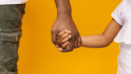 African father and daughter holding hands, orange background