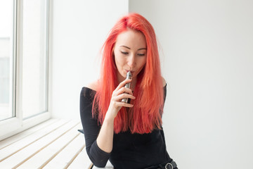 Vape, addiction and people concept - young woman with colored hair is smoking a vape