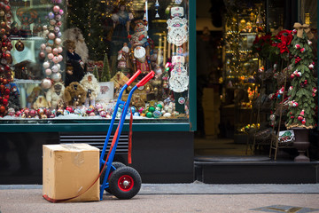 Cardboard box on a cart against Christmas decoration shop window