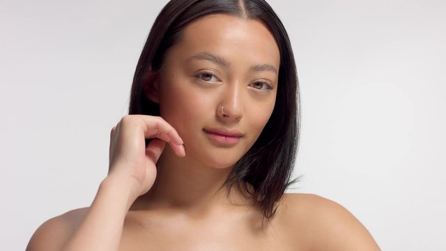 mixed race asian model in studio beauty shoot Model watching aside and then to the camera. Brown eyed model with ideal skin and natural makeup