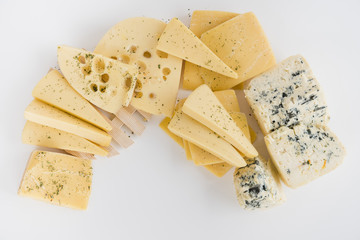 An overhead view of maasdam; cheddar; gouda and blue cheese on white backdrop