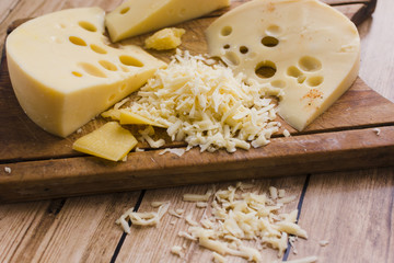 Grated and slices of emmental on chopping board over the table