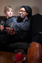 Young girl and boy drinking wine on sofa