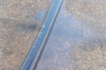 Tram rail in water puddle.