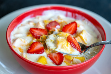 Mango, passion fruit, strawberry and yogurt brulee. Fruit dessert on breakfast with wedges of perfectly ripe in season mangoes and strawberry, covered fresh passion fruit pulp