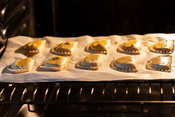 Empanadillas , small filling tuna pies in roasting tray  in oven. Cooking process background. Natural atmosphere lifestyle image.