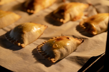 Empanadillas , small filling tuna pies in roasting tray  in oven. Cooking process background. Natural atmosphere lifestyle image.