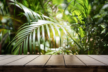Dark wood table top (Bar) with blur on green palm leaves or tree in tropical forest with bokeh...